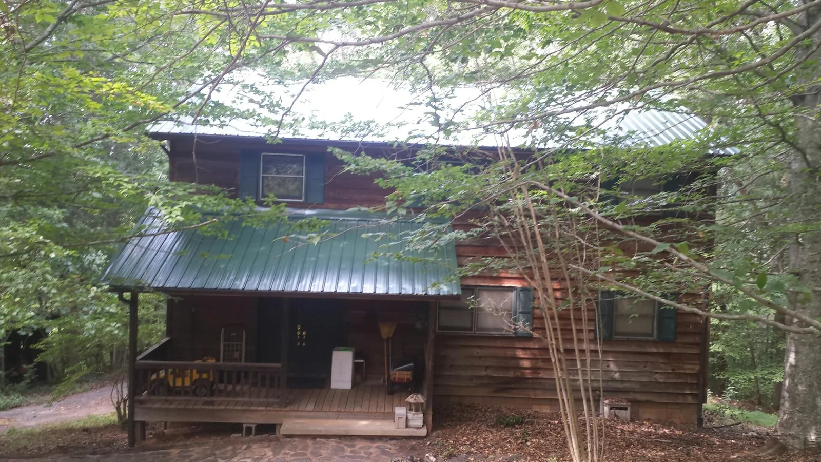 Green metal roof and covered porch on a log cabin in Schoenchen