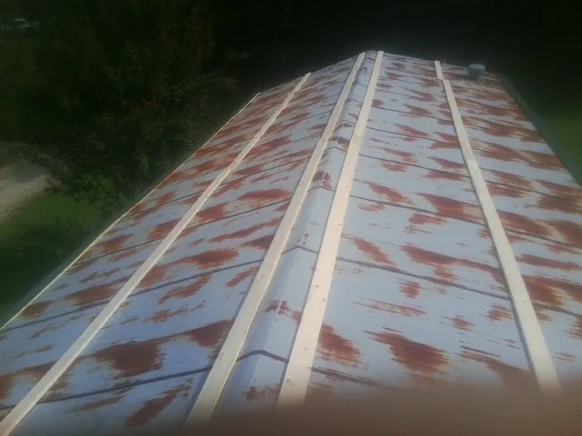 Rusted metal roof panels with new wood purlins before replacement — Storm Damage Roof Repair in Schoenchen by Roofing Brothers