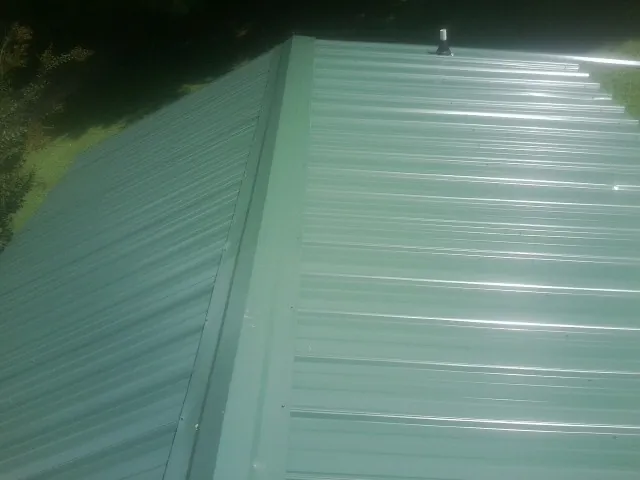 New green metal panels meeting at the ridge of a roof — Flat Roof Repair work by our crew in Schoenchen