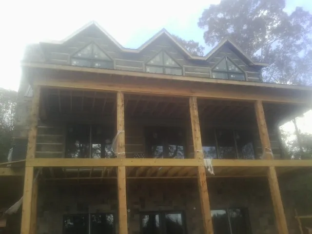 Dormers and porch framing on a large log home under construction — Roof Coating work by our crew in Schoenchen