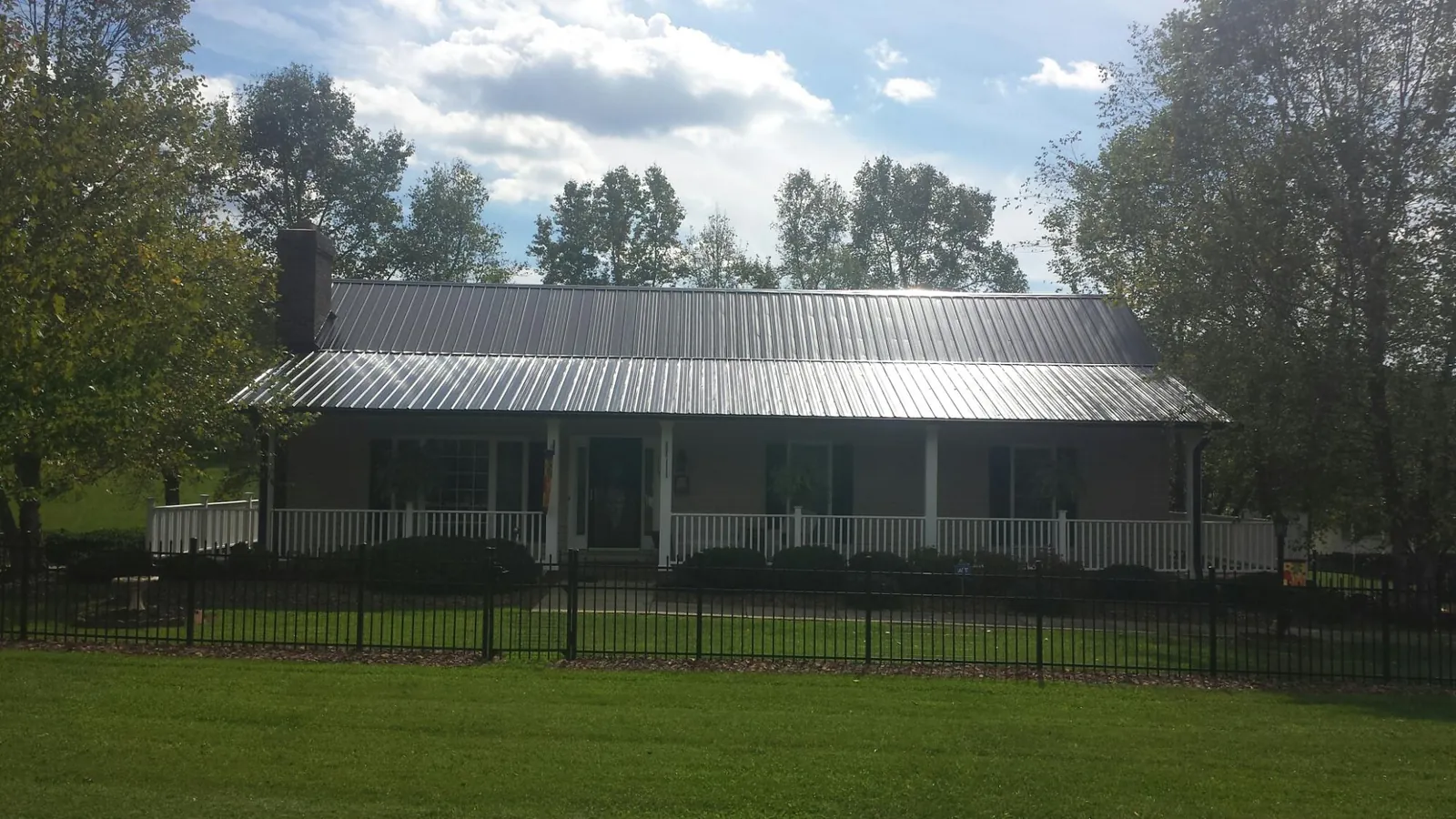 Gray metal roof on a brick ranch with a full width front porch — Gutter Guard Installation work by our crew in Schoenchen