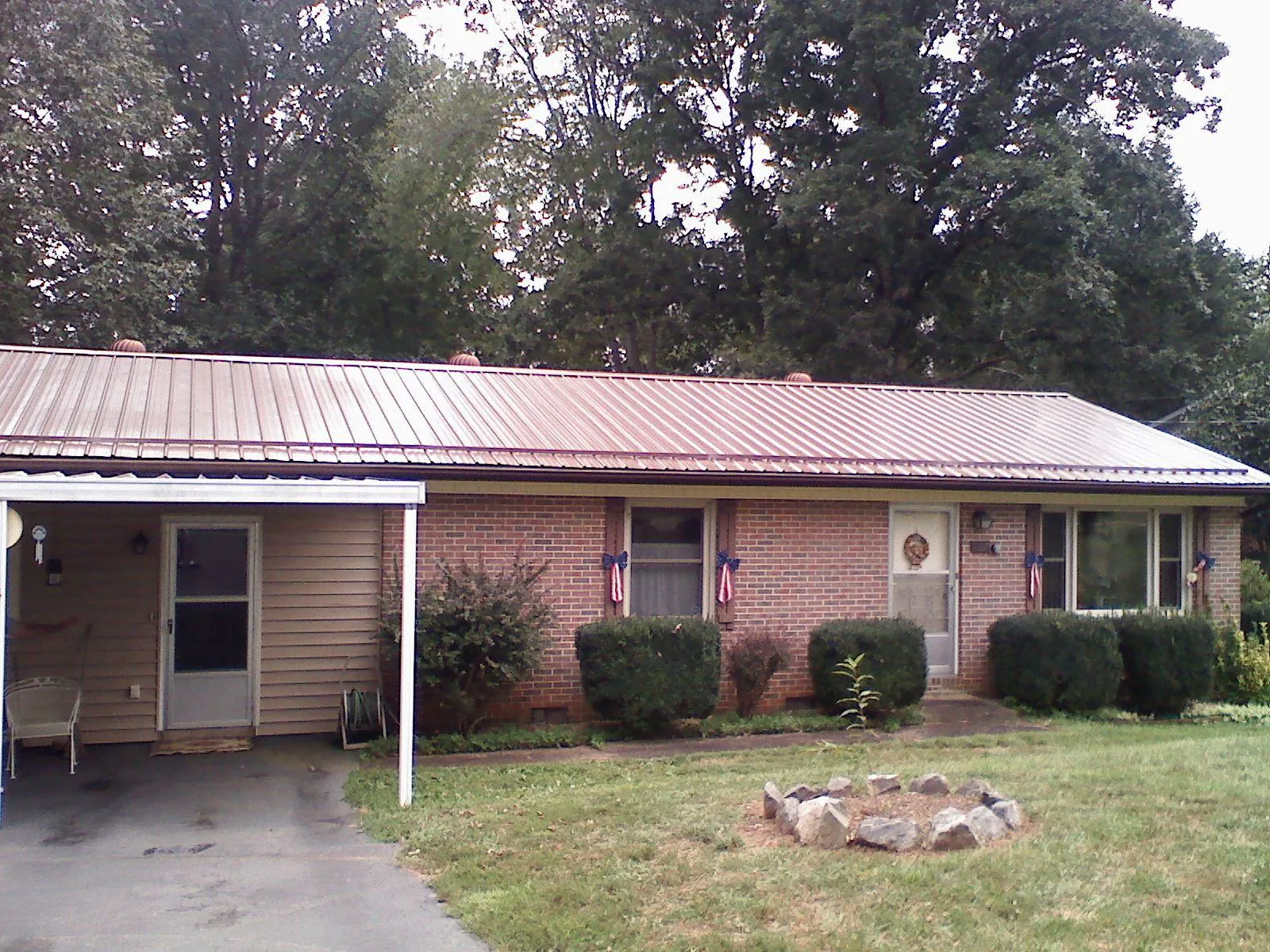 Bronze metal roof and carport on a brick ranch home — Roof Repair work by our crew in Schoenchen
