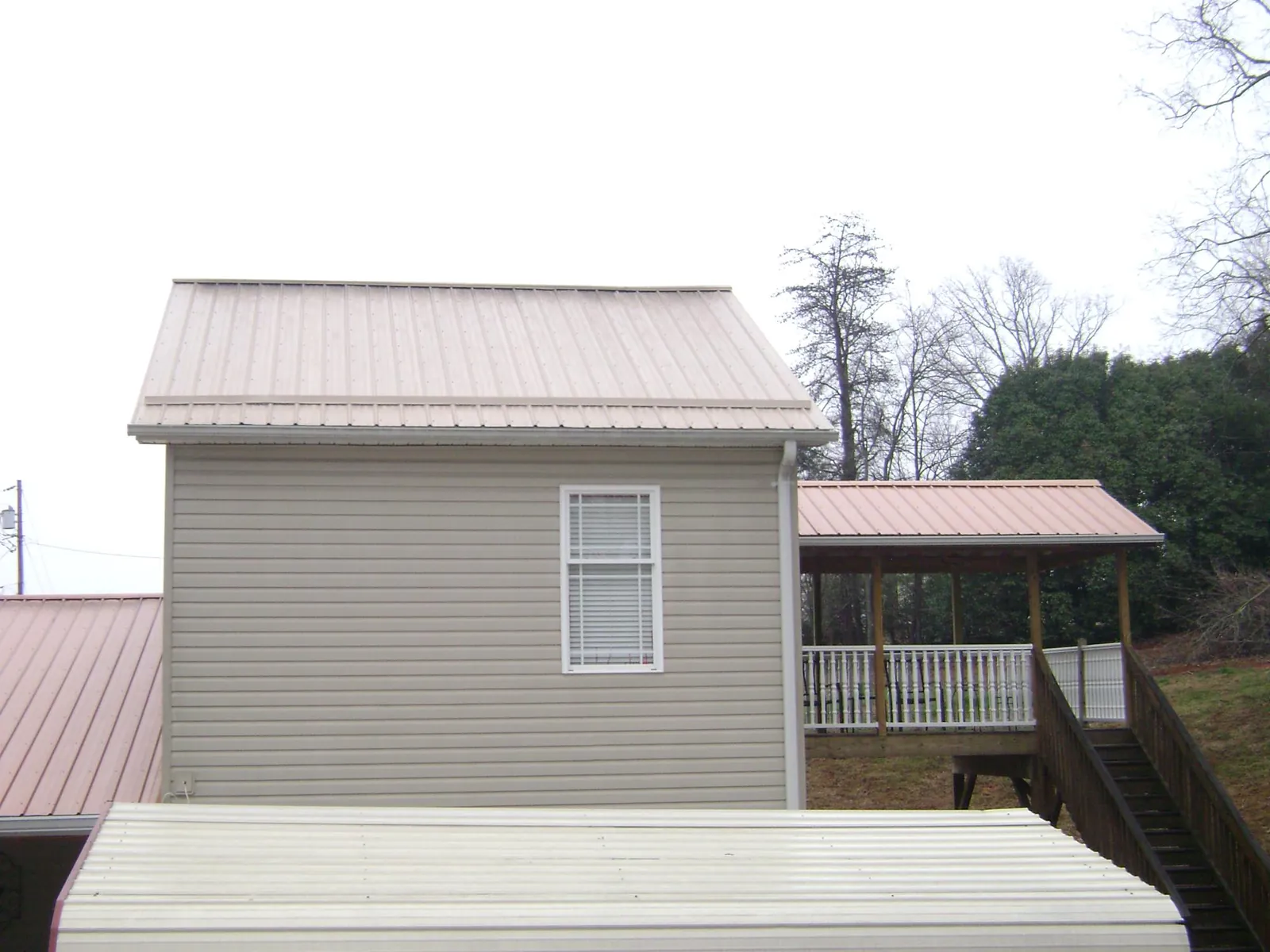 Tan metal roofs on a two story addition and attached porch, from a Roof Replacement job in Schoenchen