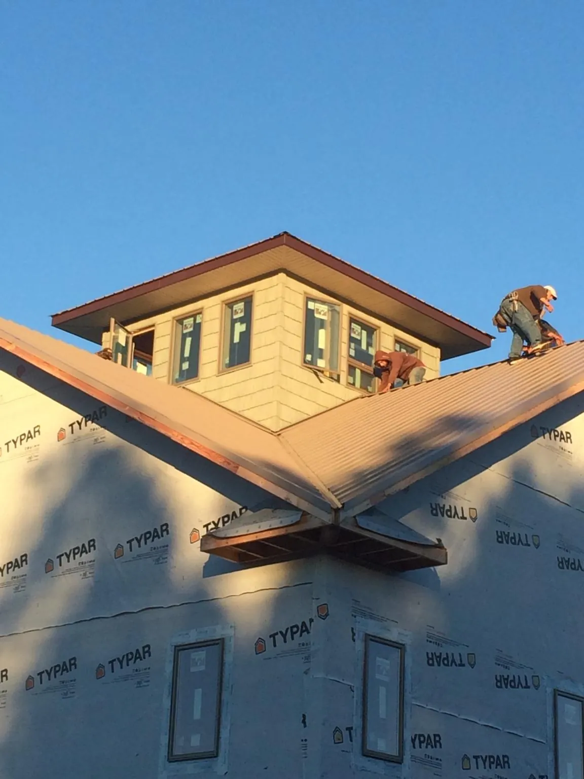 Roofers working around a rooftop cupola on a new metal roof at sunset — Roof Waterproofing in Schoenchen by Roofing Brothers